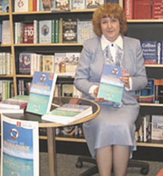 Shirley Thompson holding a copy of Adrift in Paradise at a bookshop signing